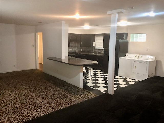 2403 Sherwood Ln, Austin, TX 78704 - kitchen with independent washer and dryer, a peninsula, tile patterned floors, dark countertops, and a kitchen breakfast bar