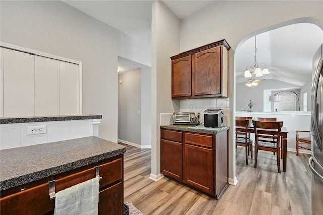 8505 Shallot Way, Austin, TX 78748 - kitchen with light wood-style floors, dark countertops, lofted ceiling, a chandelier, and arched walkways