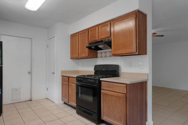 5808 Spring Meadow Rd, Austin, TX 78744 - kitchen with gas stove, under cabinet range hood, light countertops, brown cabinets, and a textured ceiling