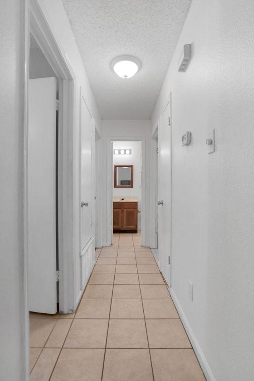 5808 Spring Meadow Rd, Austin, TX 78744 - hall with light tile patterned floors, a textured ceiling, and baseboards