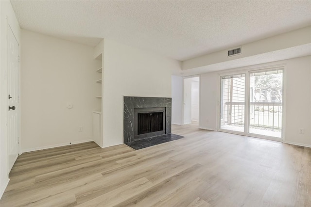 8600 Fathom Cir Unit 1303, Austin, TX 78750 - unfurnished living room with a textured ceiling, wood finished floors, a high end fireplace, and baseboards