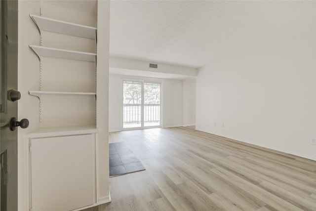 8600 Fathom Cir Unit 1303, Austin, TX 78750 - unfurnished living room featuring wood finished floors, a textured ceiling, and baseboards
