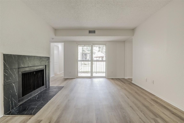 8600 Fathom Cir Unit 1303, Austin, TX 78750 - unfurnished living room with a textured ceiling, wood finished floors, a tile fireplace, and baseboards