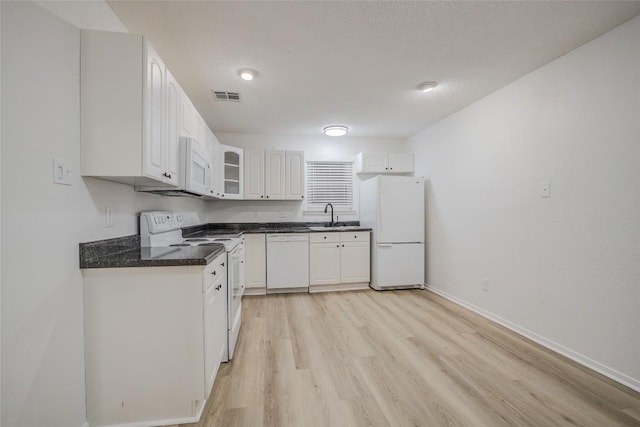 8600 Fathom Cir Unit 1303, Austin, TX 78750 - kitchen with white appliances, dark countertops, light wood-type flooring, white cabinets, and glass insert cabinets