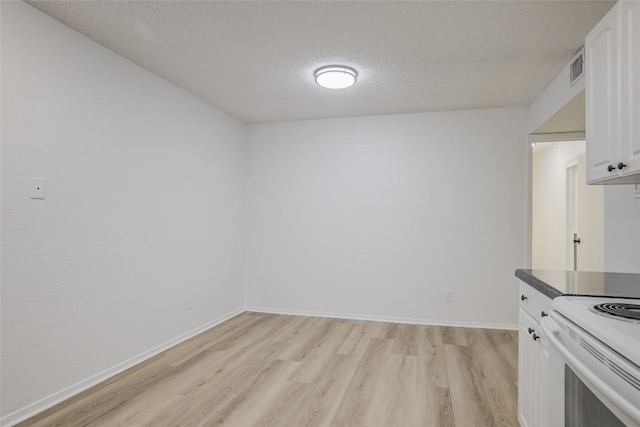 8600 Fathom Cir Unit 1303, Austin, TX 78750 - kitchen with a textured ceiling, light wood-type flooring, white cabinets, dark countertops, and electric range