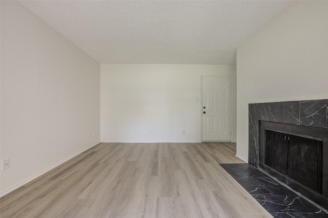 8600 Fathom Cir Unit 1303, Austin, TX 78750 - unfurnished living room featuring wood finished floors, a premium fireplace, and a textured ceiling