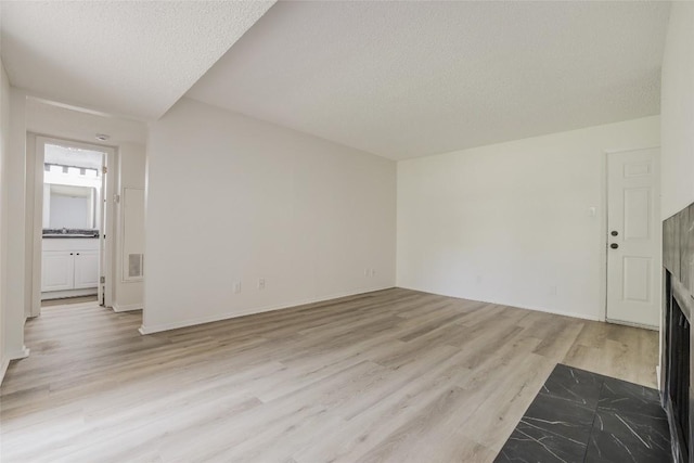 8600 Fathom Cir Unit 1303, Austin, TX 78750 - unfurnished living room featuring light wood-style floors, a textured ceiling, and a fireplace