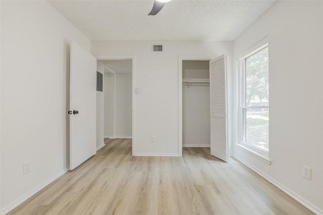 8600 Fathom Cir Unit 1303, Austin, TX 78750 - unfurnished bedroom with light wood-style floors, a textured ceiling, a closet, baseboards, and a ceiling fan