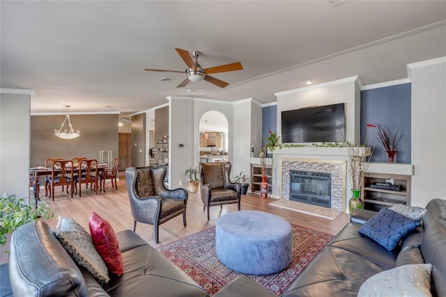 7500 Muleshoe Bend Trl, Marble Falls, TX 78654 - living room featuring ornamental molding, wood finished floors, a ceiling fan, a tiled fireplace, and a chandelier