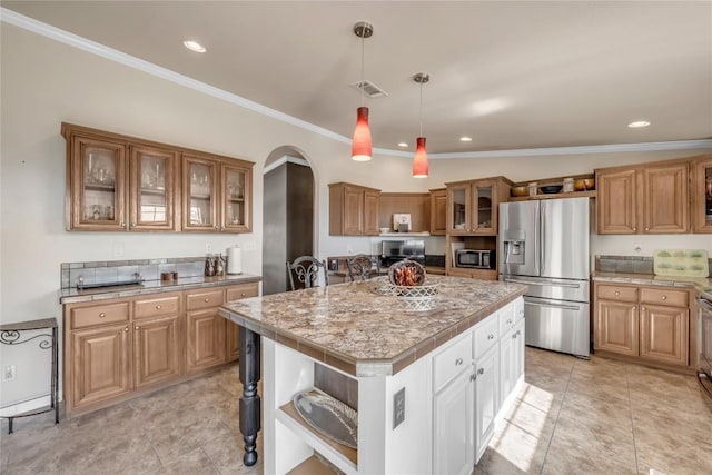 7500 Muleshoe Bend Trl, Marble Falls, TX 78654 - kitchen featuring appliances with stainless steel finishes, arched walkways, ornamental molding, a kitchen island, and light countertops