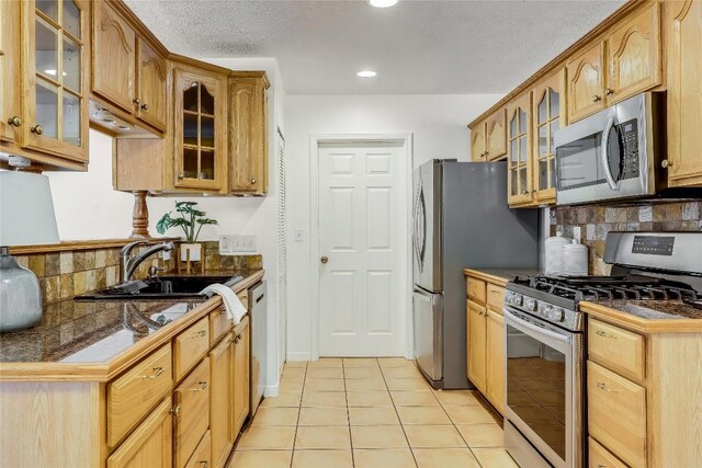 1505 Wheless Ln, Austin, TX 78723 - kitchen with appliances with stainless steel finishes, tasteful backsplash, glass insert cabinets, light tile patterned flooring, and a textured ceiling