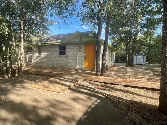 309 Stolle Ln, Flatonia, TX 78941 - back of property with a storage unit, a deck, and stone siding