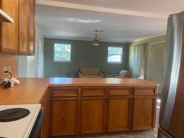 309 Stolle Ln, Flatonia, TX 78941 - kitchen featuring freestanding refrigerator, a peninsula, plenty of natural light, crown molding, and light countertops
