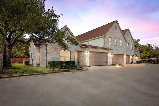 9122 Balcones Club Dr Unit 9, Austin, TX 78750 - french provincial home with cooling unit, stone siding, concrete driveway, and a garage