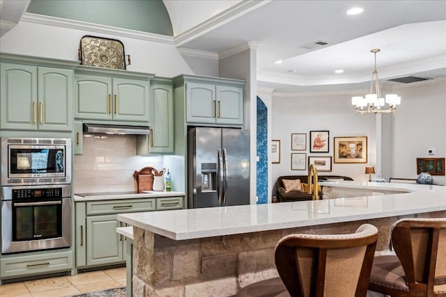 9122 Balcones Club Dr Unit 9, Austin, TX 78750 - kitchen with stainless steel appliances, green cabinets, a breakfast bar, under cabinet range hood, and tasteful backsplash