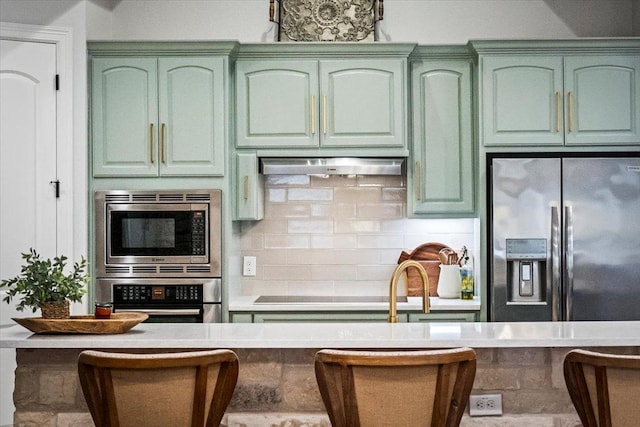 9122 Balcones Club Dr Unit 9, Austin, TX 78750 - kitchen featuring green cabinets, stainless steel appliances, backsplash, and under cabinet range hood