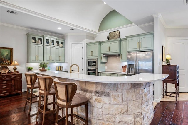 9122 Balcones Club Dr Unit 9, Austin, TX 78750 - kitchen with stainless steel appliances, green cabinetry, dark wood-style floors, crown molding, and light countertops