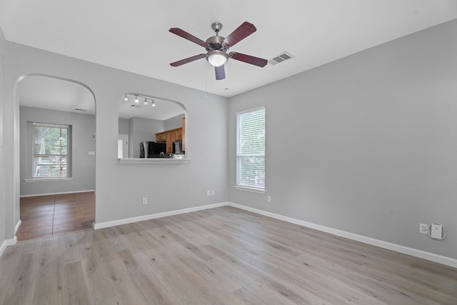 2009 Campfield Pkwy, Austin, TX 78745 - unfurnished living room featuring ceiling fan, light wood-style floors, and arched walkways