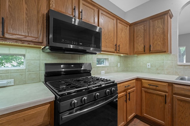 2009 Campfield Pkwy, Austin, TX 78745 - kitchen with stainless steel microwave, black range with gas stovetop, light countertops, and brown cabinets