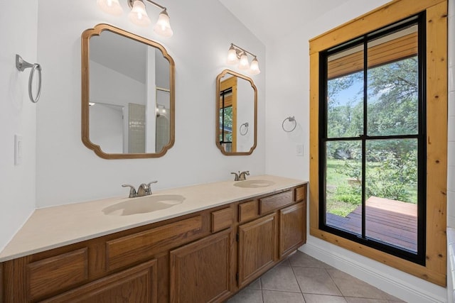 16202 Kicking Bird Dr, Leander, TX 78641 - bathroom with healthy amount of natural light, tile patterned flooring, double vanity, vaulted ceiling, and baseboards