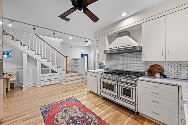 4517 Ave G, Austin, TX 78751 - kitchen with wall chimney exhaust hood, range with two ovens, and white cabinetry