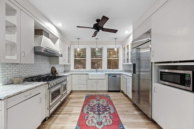 4517 Ave G, Austin, TX 78751 - kitchen featuring high quality appliances, wall chimney range hood, ceiling fan, decorative backsplash, and light wood-type flooring
