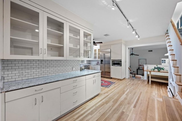 4517 Ave G, Austin, TX 78751 - kitchen featuring a ceiling fan, built in appliances, backsplash, white cabinets, and light wood-style floors