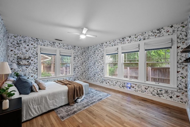 4517 Ave G, Austin, TX 78751 - bedroom featuring wallpapered walls, wood finished floors, multiple windows, and a ceiling fan