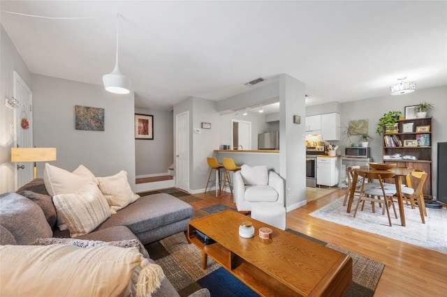 5616 Emerald Forest Dr Unit 111, Austin, TX 78745 - living area with light wood-style floors, baseboards, track lighting, and stairway