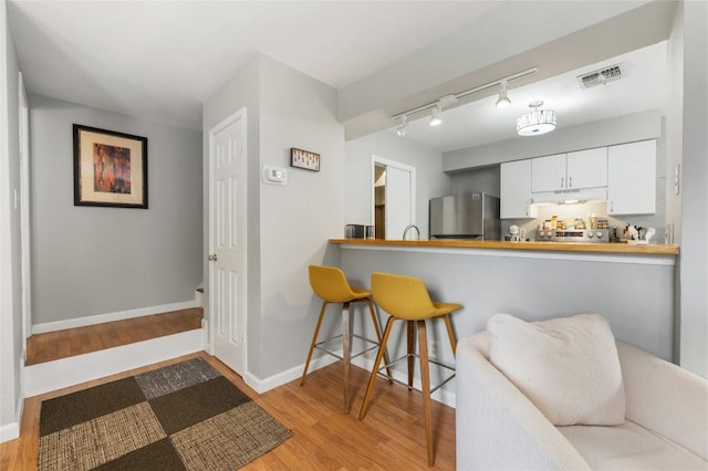 5616 Emerald Forest Dr Unit 111, Austin, TX 78745 - kitchen featuring freestanding refrigerator, under cabinet range hood, wood finished floors, and track lighting