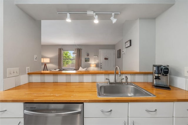 5616 Emerald Forest Dr Unit 111, Austin, TX 78745 - kitchen with stainless steel dishwasher, wood counters, a sink, rail lighting, and white cabinets