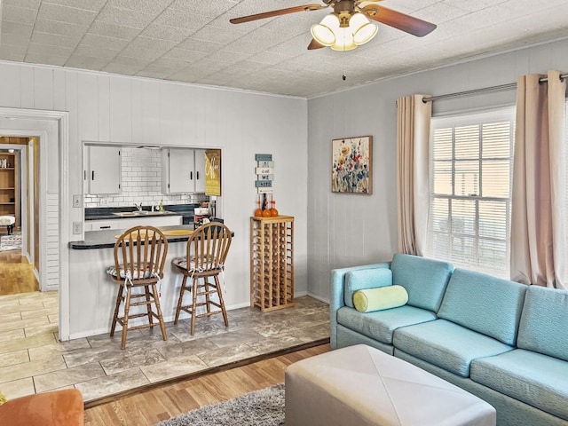 206 S Clear St, San Saba, TX 76877 - living area with a ceiling fan, crown molding, light wood-style floors, and wood walls