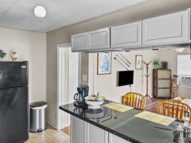 206 S Clear St, San Saba, TX 76877 - kitchen featuring freestanding refrigerator, tile countertops, light tile patterned floors, and cooling unit