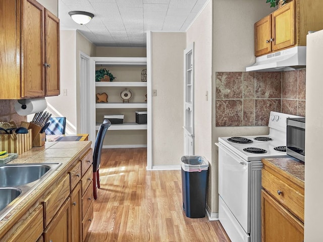 206 S Clear St, San Saba, TX 76877 - kitchen with under cabinet range hood, electric stove, light wood-style flooring, and brown cabinetry
