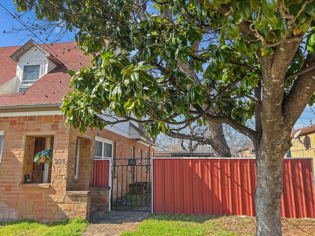 206 S Clear St, San Saba, TX 76877 - view of property exterior featuring stone siding, a gate, and roof with shingles