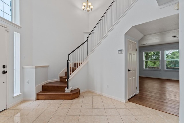 4424 Campo Verde Dr, Austin, TX 78749 - foyer featuring stairs, light tile patterned floors, a chandelier, a towering ceiling, and baseboards