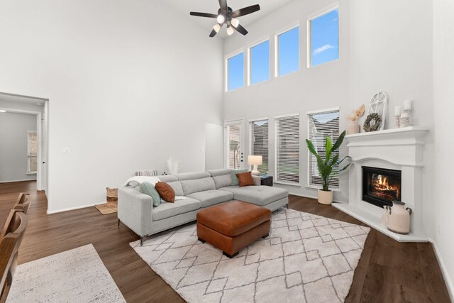 170 Fawn River Run, Kyle, TX 78640 - living area with a high ceiling, a glass covered fireplace, ceiling fan, wood finished floors, and baseboards