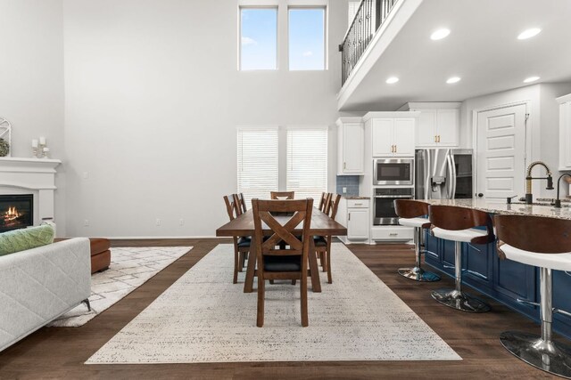 170 Fawn River Run, Kyle, TX 78640 - dining space with dark wood-style floors, a glass covered fireplace, a high ceiling, recessed lighting, and baseboards