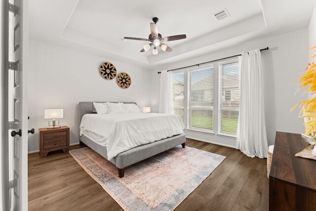 170 Fawn River Run, Kyle, TX 78640 - bedroom with a raised ceiling, dark wood-style flooring, a ceiling fan, and baseboards