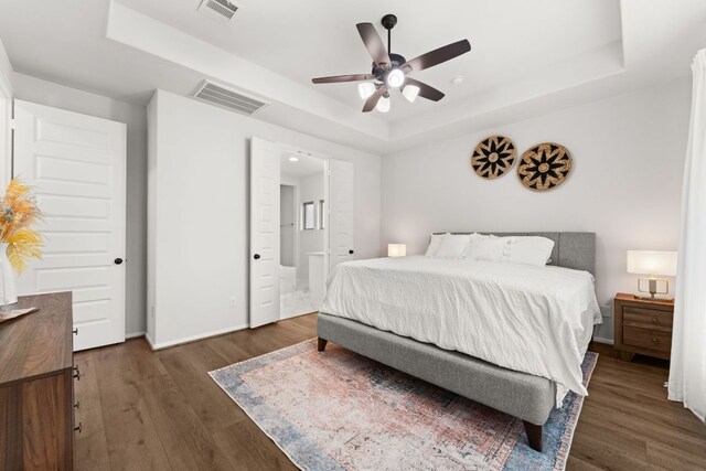 170 Fawn River Run, Kyle, TX 78640 - bedroom featuring a tray ceiling, wood finished floors, baseboards, ceiling fan, and connected bathroom