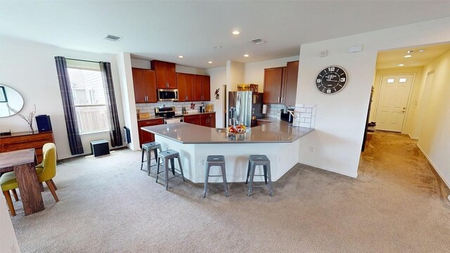 11405 Kirkland Hill Path, Austin, TX 78754 - kitchen with appliances with stainless steel finishes, a peninsula, light colored carpet, a breakfast bar, and backsplash