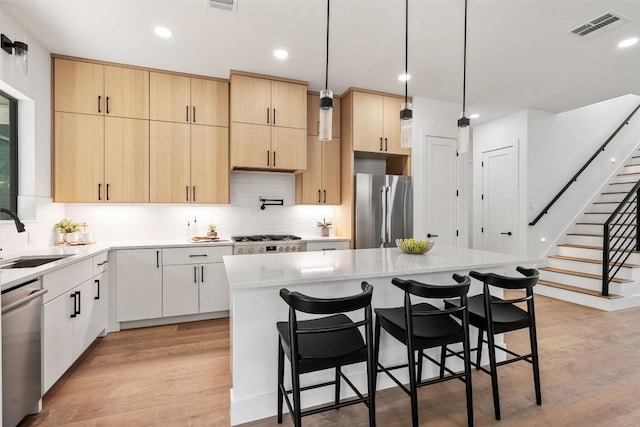 2303 Westworth Cir, Austin, TX 78704 - kitchen featuring appliances with stainless steel finishes, a sink, light brown cabinets, light wood-style flooring, and recessed lighting