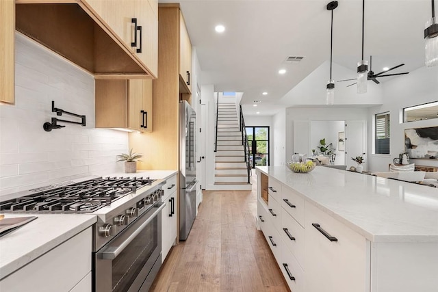 2303 Westworth Cir, Austin, TX 78704 - kitchen featuring stainless steel appliances, ceiling fan, decorative backsplash, open floor plan, and light wood-style flooring