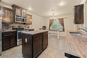 205 W Little Dipper Dr, Killeen, TX 76542 - kitchen with stainless steel appliances, a sink, a kitchen island, dark brown cabinets, and pendant lighting