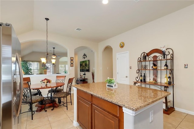 2002 S Ash Cv, Hutto, TX 78634 - kitchen featuring stainless steel fridge, light tile patterned flooring, light stone countertops, a kitchen island, and hanging light fixtures