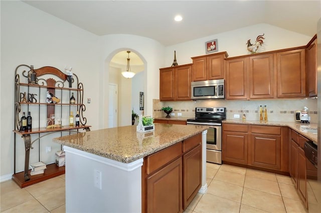 2002 S Ash Cv, Hutto, TX 78634 - kitchen featuring stainless steel appliances, light stone countertops, tasteful backsplash, light tile patterned floors, and a kitchen island