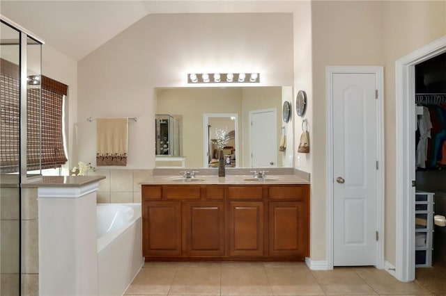 2002 S Ash Cv, Hutto, TX 78634 - bathroom with a spacious closet, double vanity, a bath, tile patterned floors, and vaulted ceiling