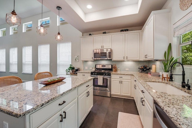 7709 Menchaca Rd Unit 16, Austin, TX 78745 - kitchen with appliances with stainless steel finishes, a sink, backsplash, white cabinetry, and a kitchen island