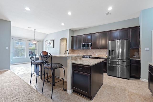 3217 Falconers Way, Pflugerville, TX 78660 - kitchen featuring stainless steel appliances, backsplash, arched walkways, light stone counters, and vaulted ceiling