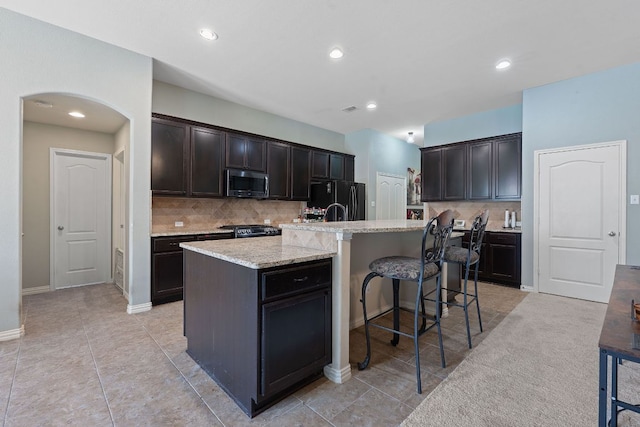 3217 Falconers Way, Pflugerville, TX 78660 - kitchen featuring stainless steel microwave, backsplash, freestanding refrigerator, a kitchen island with sink, and a breakfast bar area